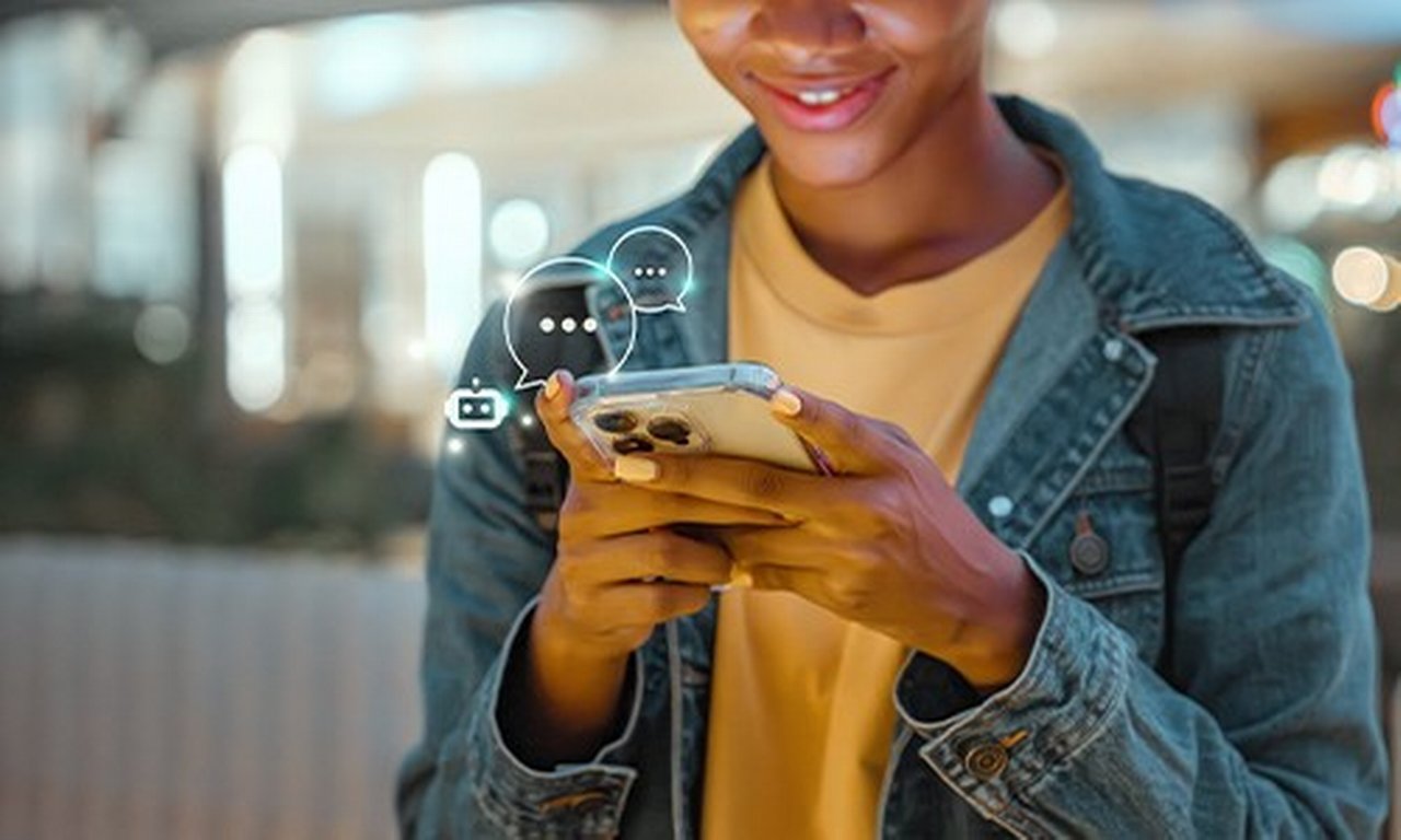 Young person smiling while looking at a mobile.