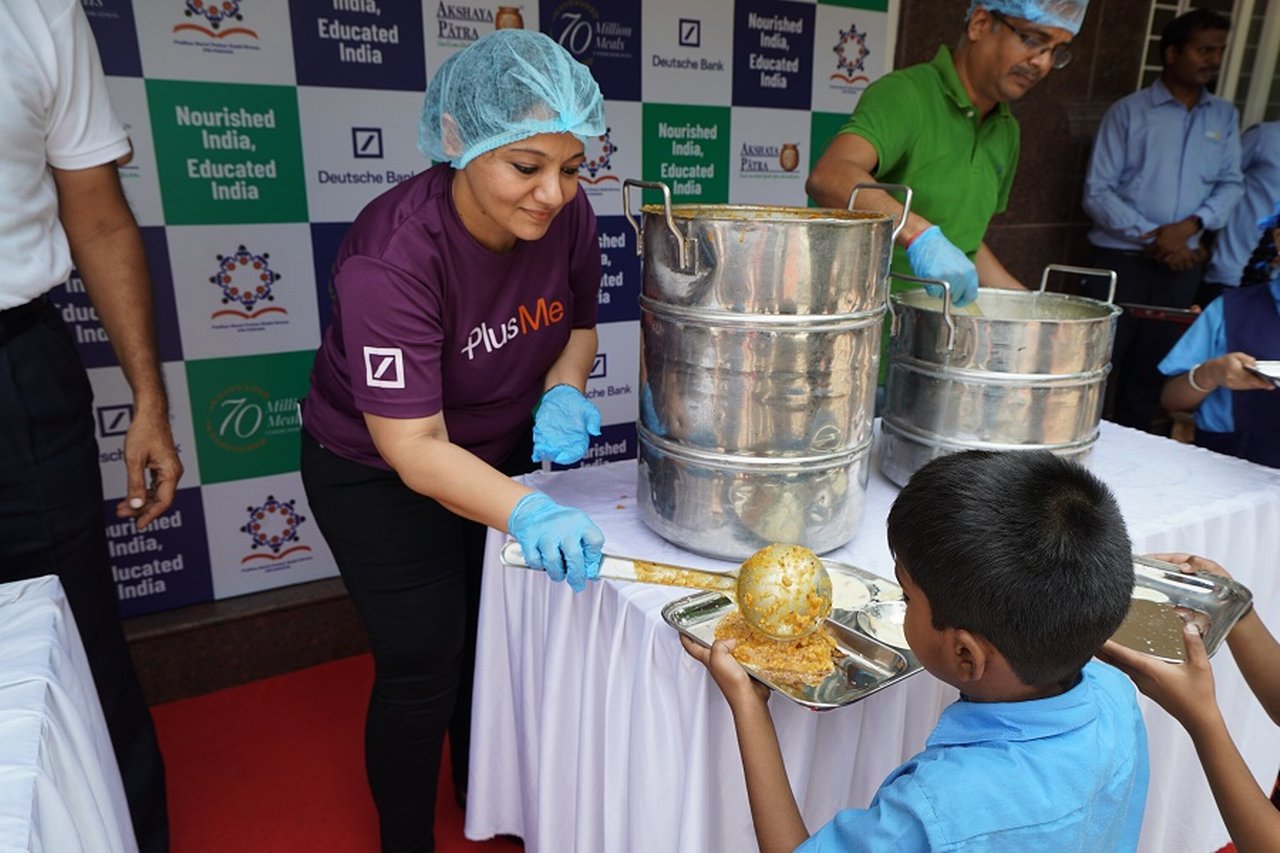 Volunteer distributes food to a young boy in India