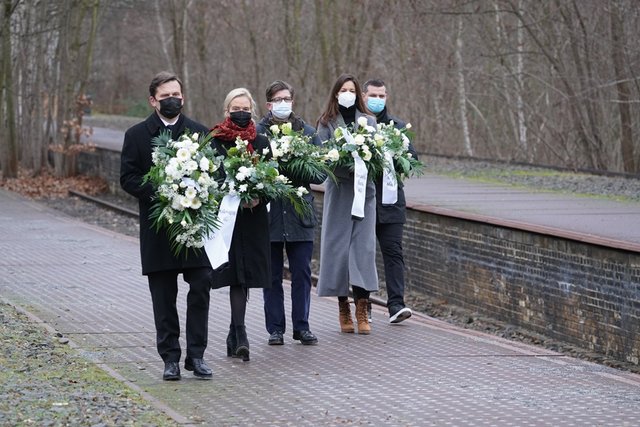 Fünf Personen tragen Kränze bei einer Gedenkveranstaltung am Mahnmal Gleis 17 am Bahnhof Grunewald.