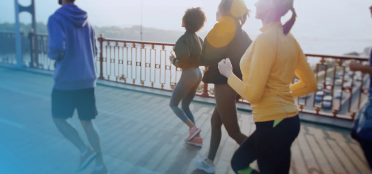 People jogging across a bridge in morning light.