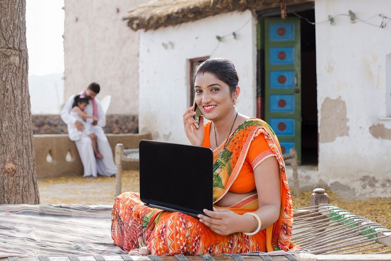 Rural woman talking on the phone with a laptop on her lap