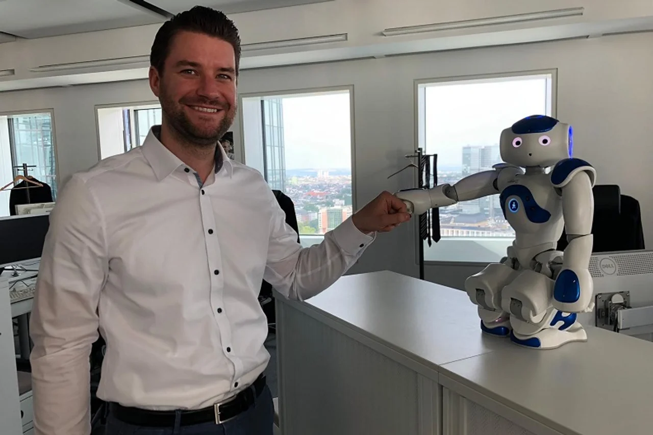 Max Mindt und ein Roboter begrüßen sich