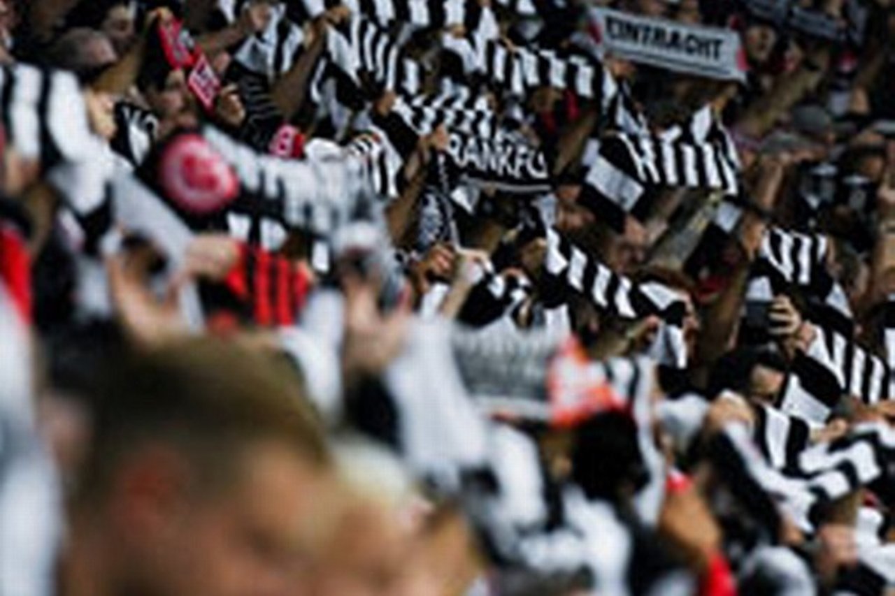 Eintracht Frankfurt fans waving black and white striped scarves in Deutsche Bank Park stadium