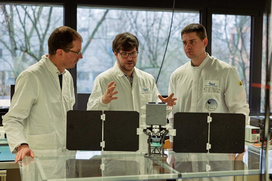 Daiberl and Segert discussing in front of a satellite model