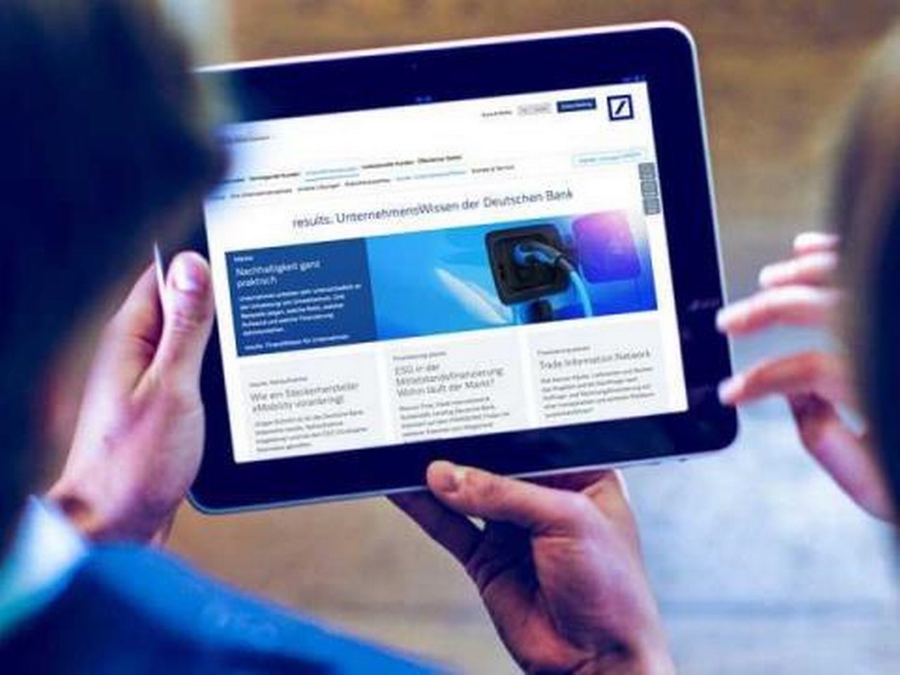 Zwei Personen betrachten „results.“, die Unternehmenswissen-Website, auf einem Tablet