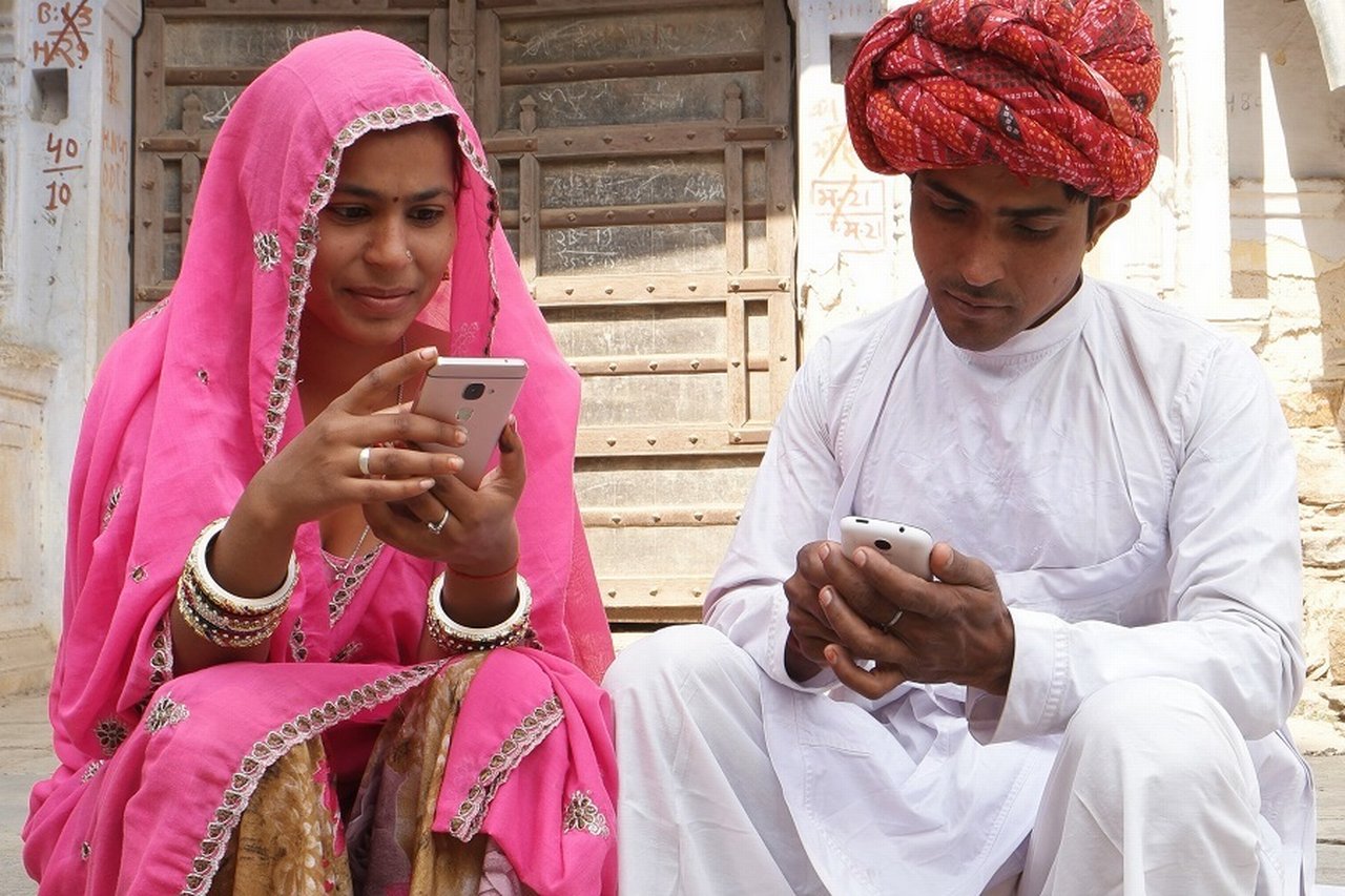 Woman and man in traditional Indian clothing looking at their mobile phones