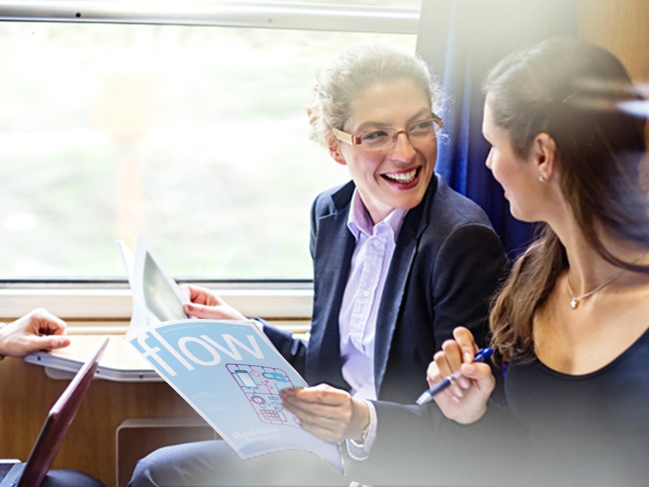 Young professionals reading the flow magazine and discussing on a train