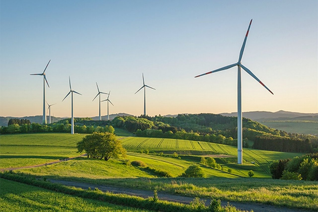 Windräder zur Erzeugung erneuerbarer Energie in einer grünen Hügellandschaft.