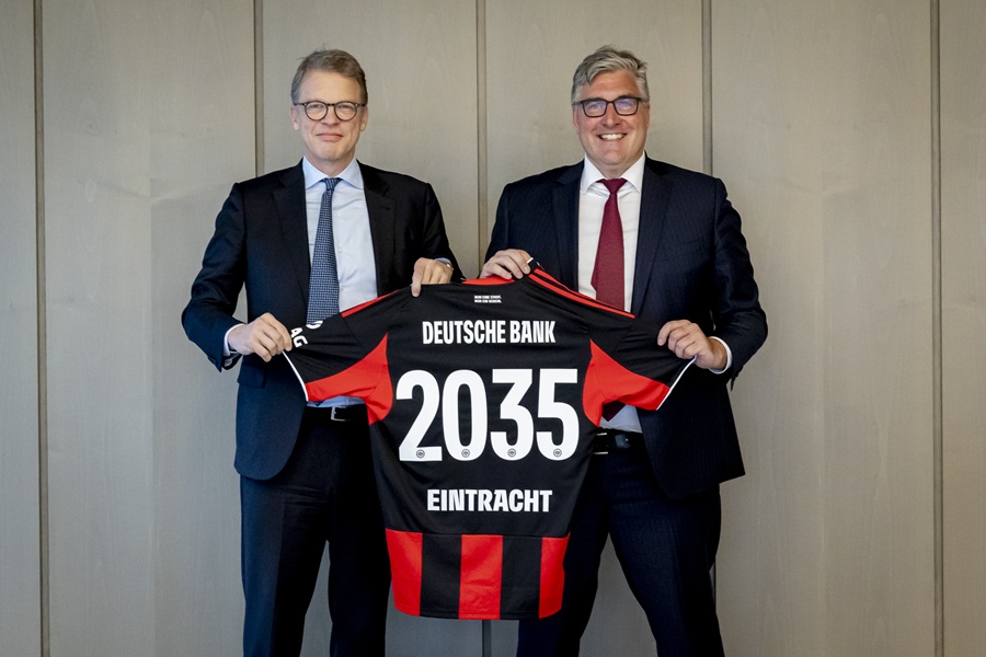 Christian Sewing and Axel Hellmann celebrate the Deutsche Bank-Eintracht partnership extension until 2035, holding a black and red Eintracht Jersey.